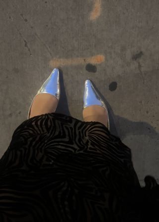 Woman wearing black sheer dress with silver Sam Edelman shoes.