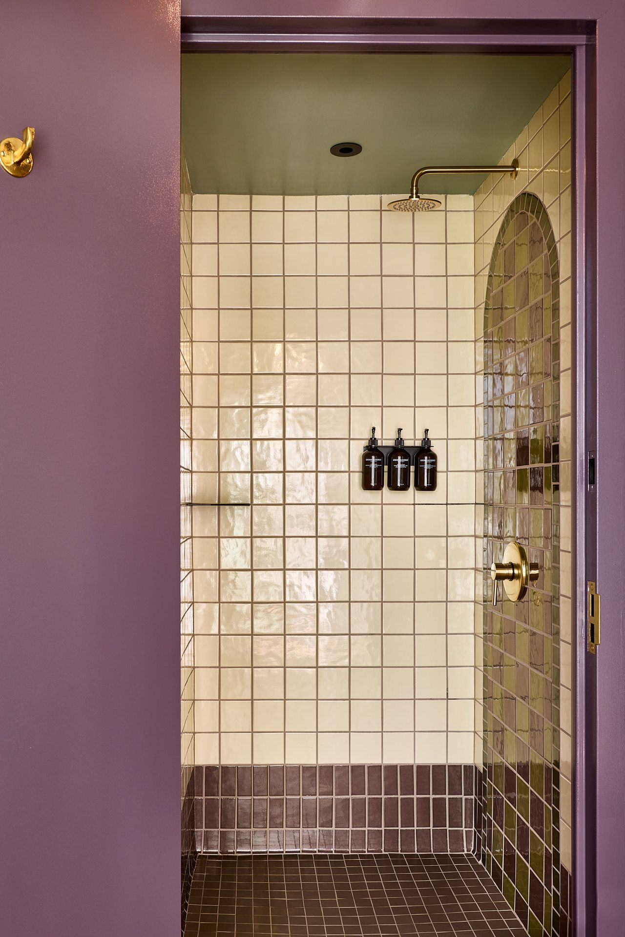 A sleeper train-inspired hotel features capsule-style rooms drenched in pale wood, stripy upholstery in red and cream, and Art Deco accents, including a tiled, purple-tinted shower and a murals-covered wall.