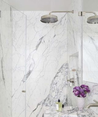 An oversized showerhead in a marble shower