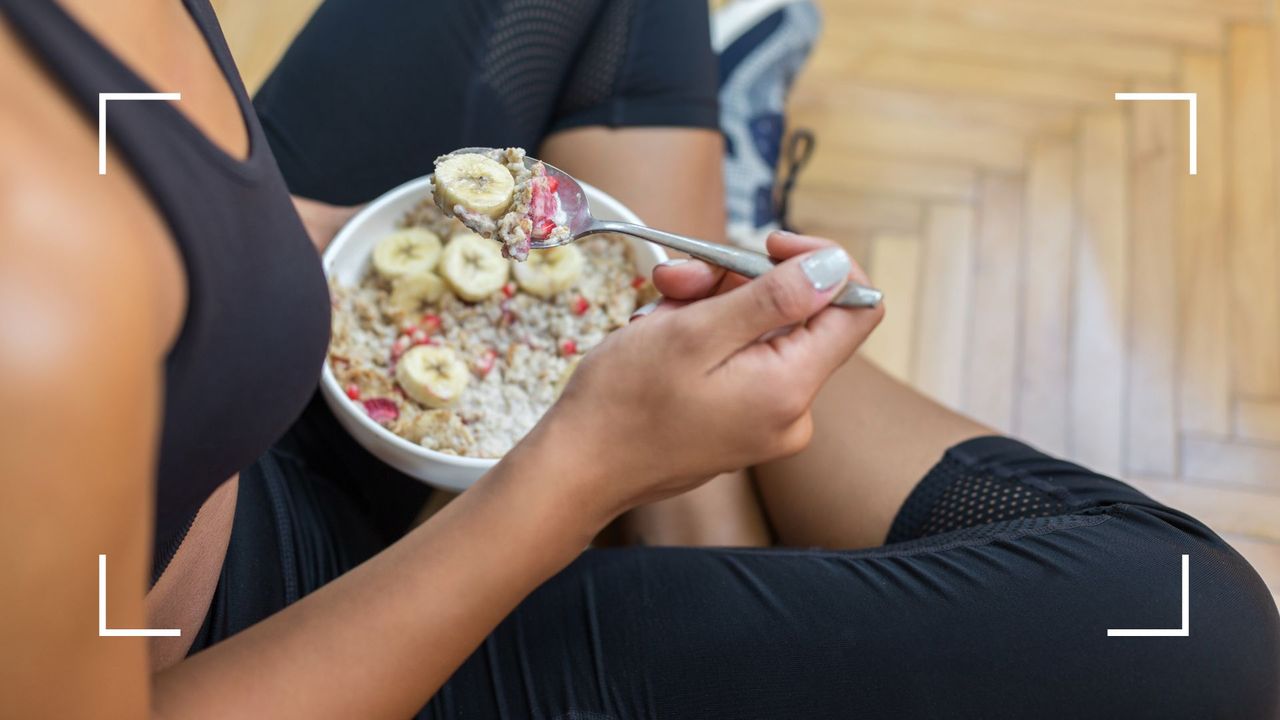 Woman eating a bowl of porridge wearing black activewear, after learning whether to eat before or after a workout