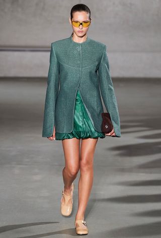 a model on the spring tory burch runway wearing a green ballon skirt with a tailored blazer and tan mary janes