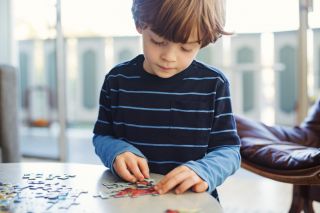 Boy solving jigsaw puzzle at home