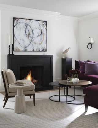 White living room with black fireplace, purple sofa and black and white abstract wall art