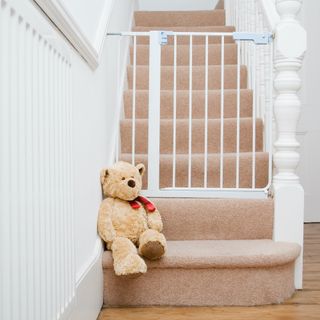 Teddy bear on stairs next to stair gate