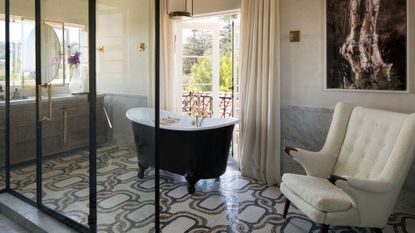 bathroom with tiled floor, black freestanding bath and brass hardware