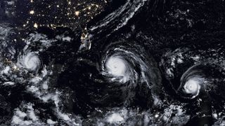 A nighttime satellite photo showing three hurricanes in a line