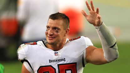 NFL star Rob Gronkowski smiles and waves as he walks of the field.