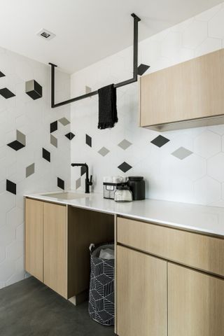 A small laundry room with wooden cabinets and minimalist abstract tiling