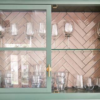 kitchen green shelves with pink tiles and wine glasses