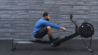 Man in workout gear using rowing machine in gym