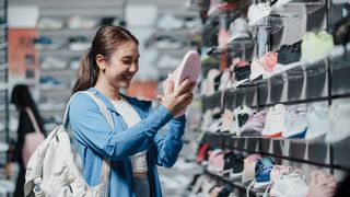 A young woman shopping for running shoes in a store