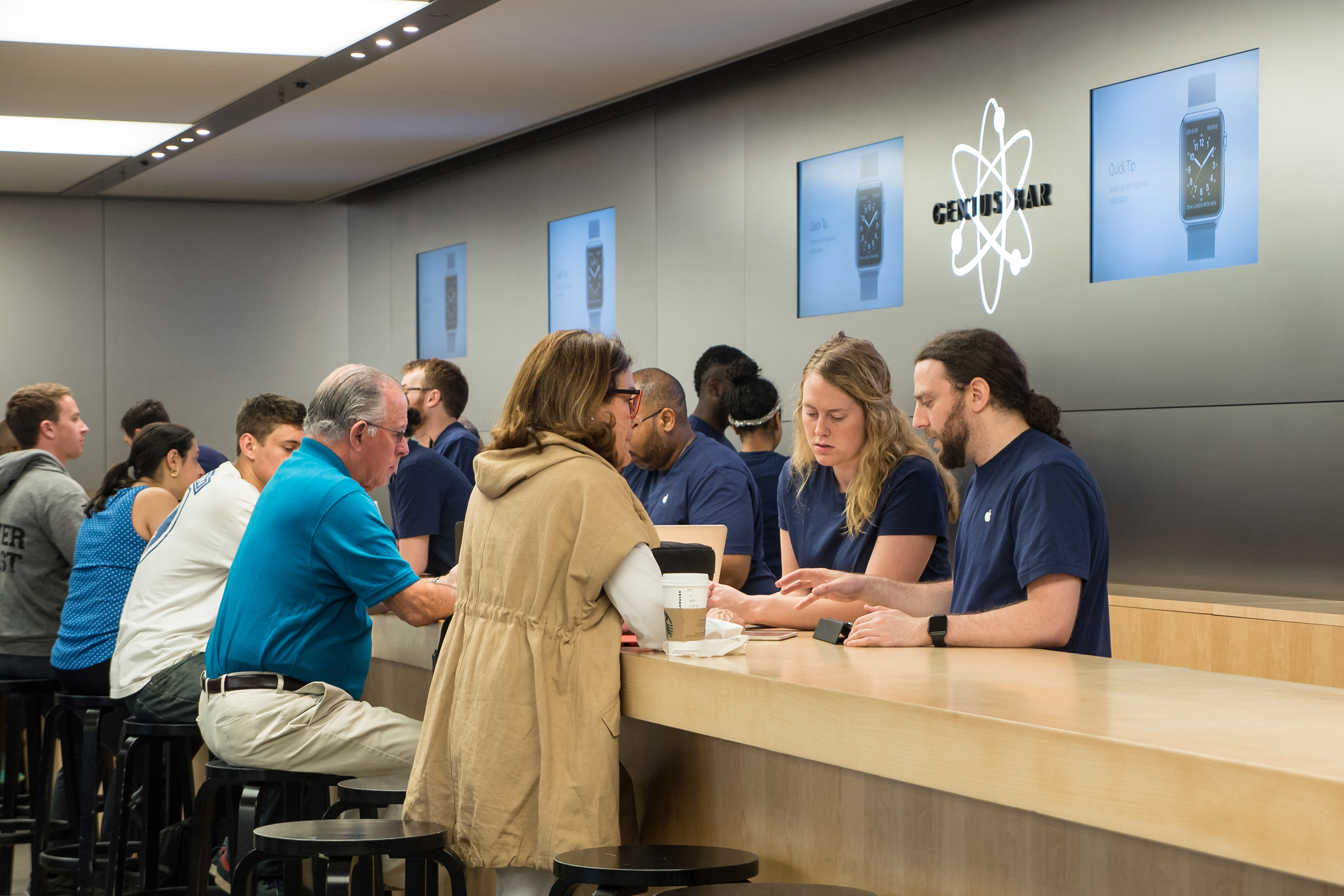 People at Genius Bar inside Apple store.