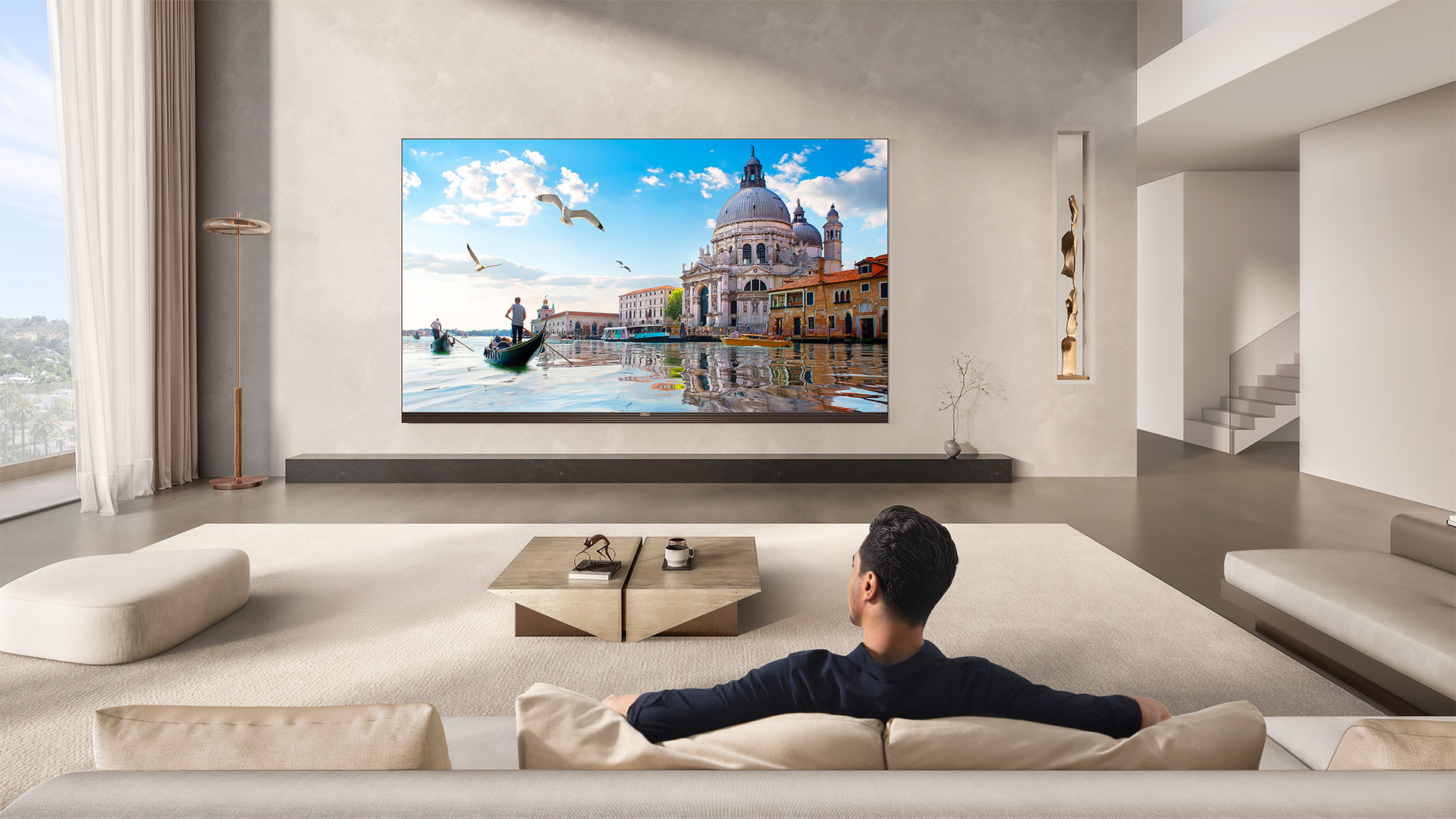Lifestyle image of person watching colourful content on the TCL X11L SQD Mini LED TV in a living room environment.