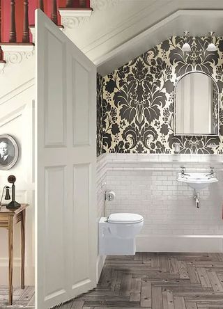 downstairs toilet under the stairs with black and white flock wallpaper and compact basin and toilet