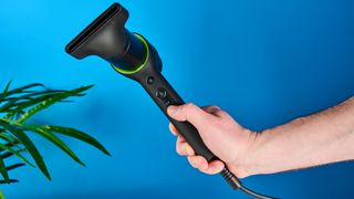 the heist 3.0 men's hair dryer in black with a bright green ring and magnetic attachment photographed against a blue background