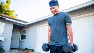 Man holding dumbbells outside a garage