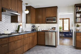 A mid-century kitchen with wooden cabinets and white tiles with a navy backplash