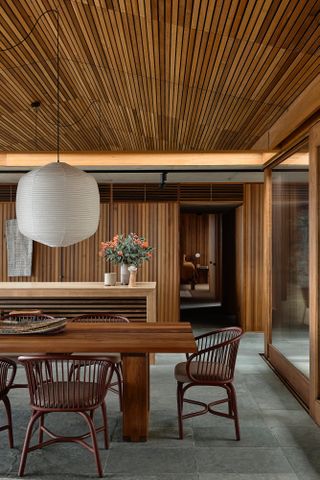 Dining room with wood-panelled walls and ceiling, wooden table and chairs