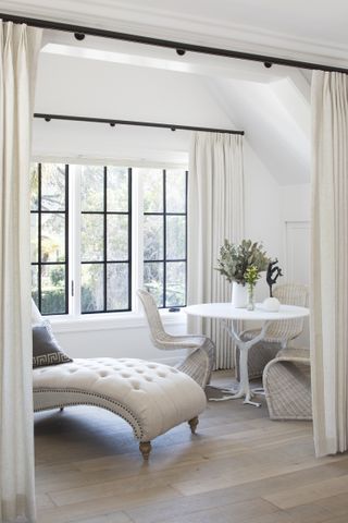 Corner of a bedroom, with white seating by a big window