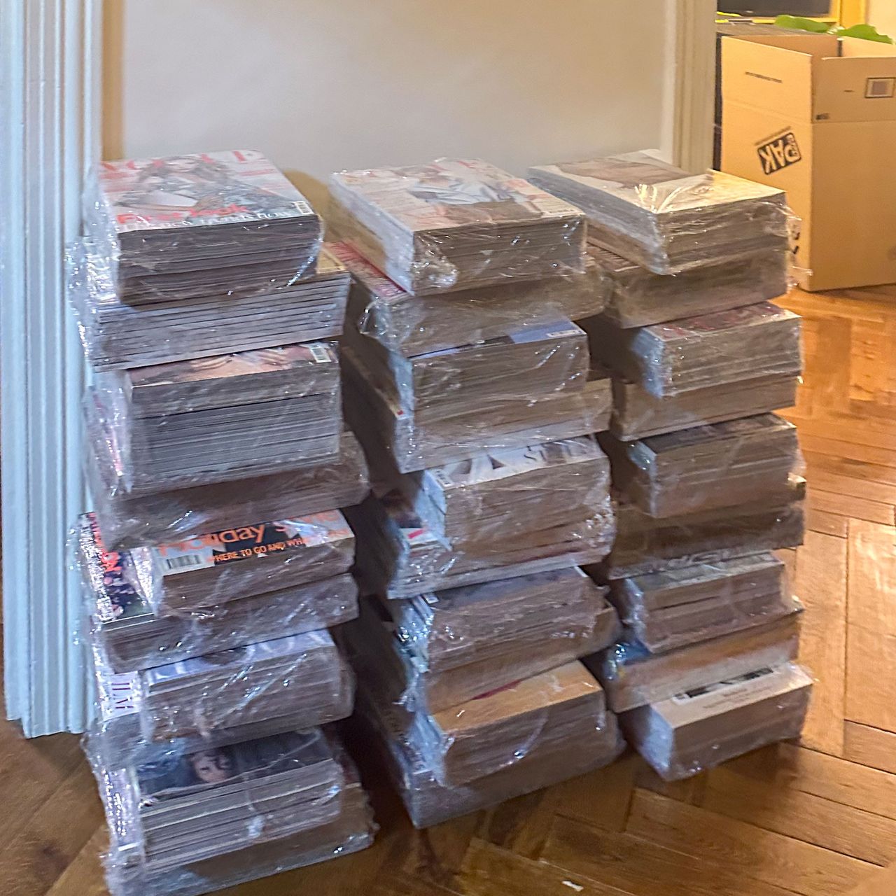 Three large piles of stacks of magazines wrapped up in plastic
