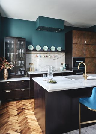 Kitchen with dark and copper finish cabinets, island, teal wall and wood floor