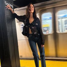 Alexa Chung wears skinny jeans with black patent leather ballet flats and a sheer blouse.