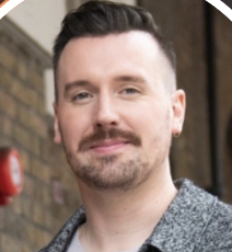 a white man with a mustache in a gray shirt