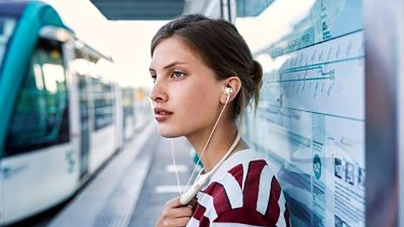 Woman wearing JBL Live 220BT Wireless neckband earbuds.