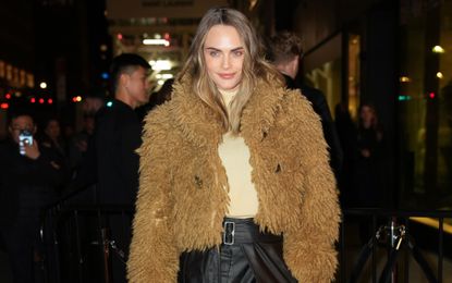 Cara Delevingne wearing a furry bolero jacket with a butter yellow top and leather maxi skirt