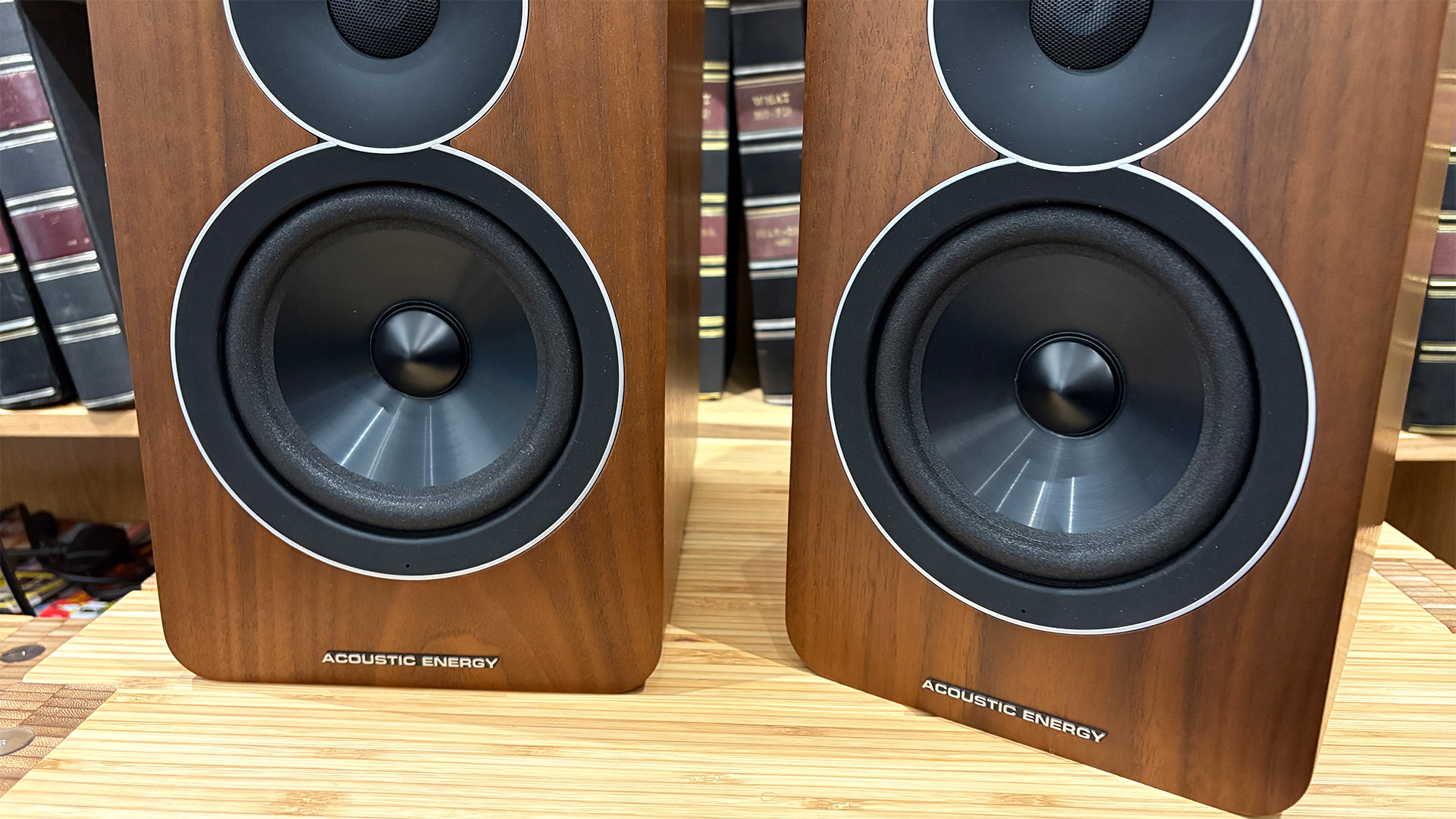 Acoustic Energy AE Active active speakers on hi-fi rack in front of bookcase focus on mid/bass units