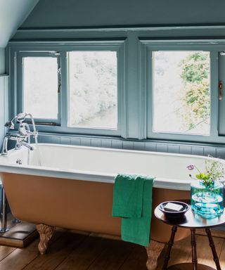 bathroom with blue walls, row of windows, roll-top bath with orange exterior