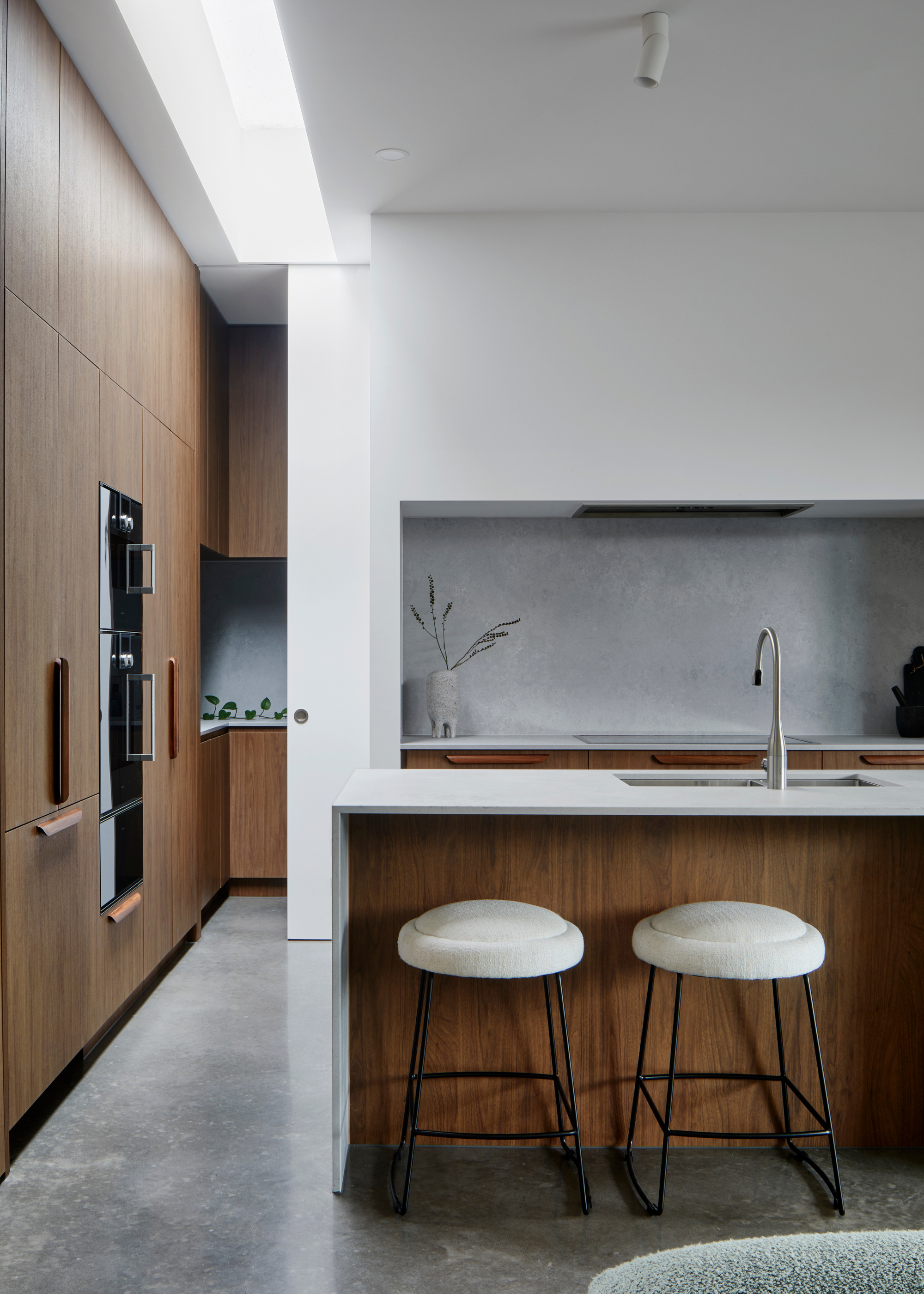 A small kitchen with a wooden accents, white walls and a textured paint backsplash