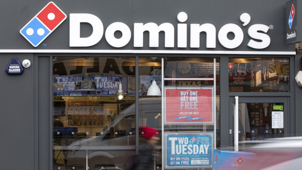 A Domino&#039;s Pizza sign stands above the entrance to a Domino&#039;s Pizza Group Plc store in Hanwell, London, U.K., on Monday, Feb. 27, 2017. Domino&#039;s Pizza said given continued strong new store performance and positive outlook both for its market and brand, it is increasing its long term target for the U.K. to 1,600 stores.