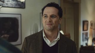 Matthew Rhys' Tom smiling in a blazer while trying to impress the New York Times journalist in Widow's Bay. 