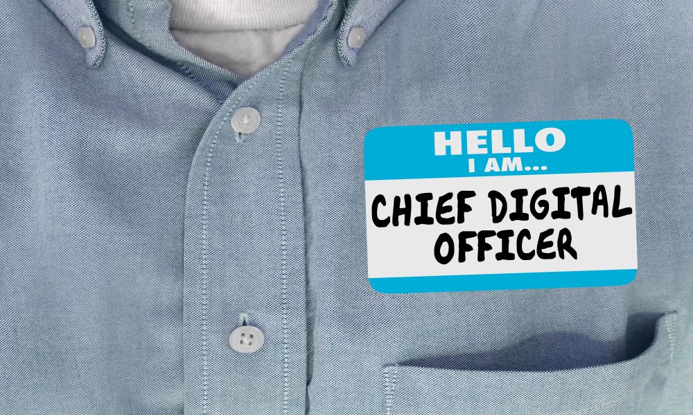 A man in a shirt wearing a &amp;#039;Hello, I am a chief digital officer&amp;#039; sticker