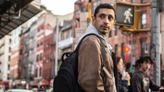 Riz Ahmed with a backpack near a crosswalk in Relay
