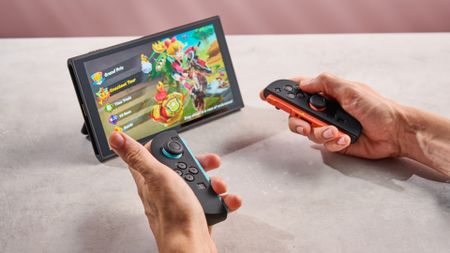 A man holds the Joy-Con 2, showing off the Snakebyte silicone grips that have been applied to them.