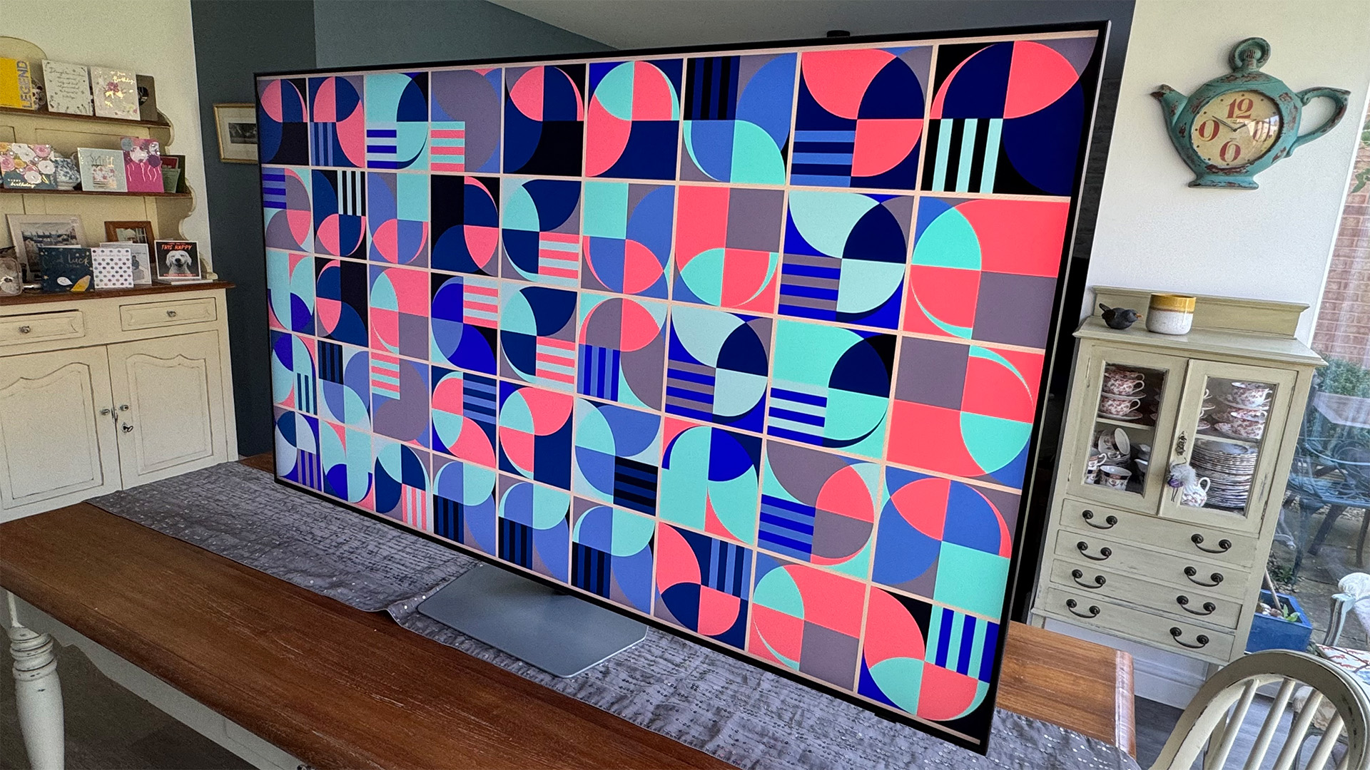 Samsung QN90F Mini LED TV on dining table with colourful pattern on screen