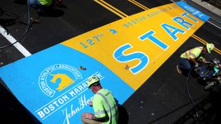 James Sawler, of RoadSafe Traffic Systems, paints the starting line for the 2023 Boston Marathon