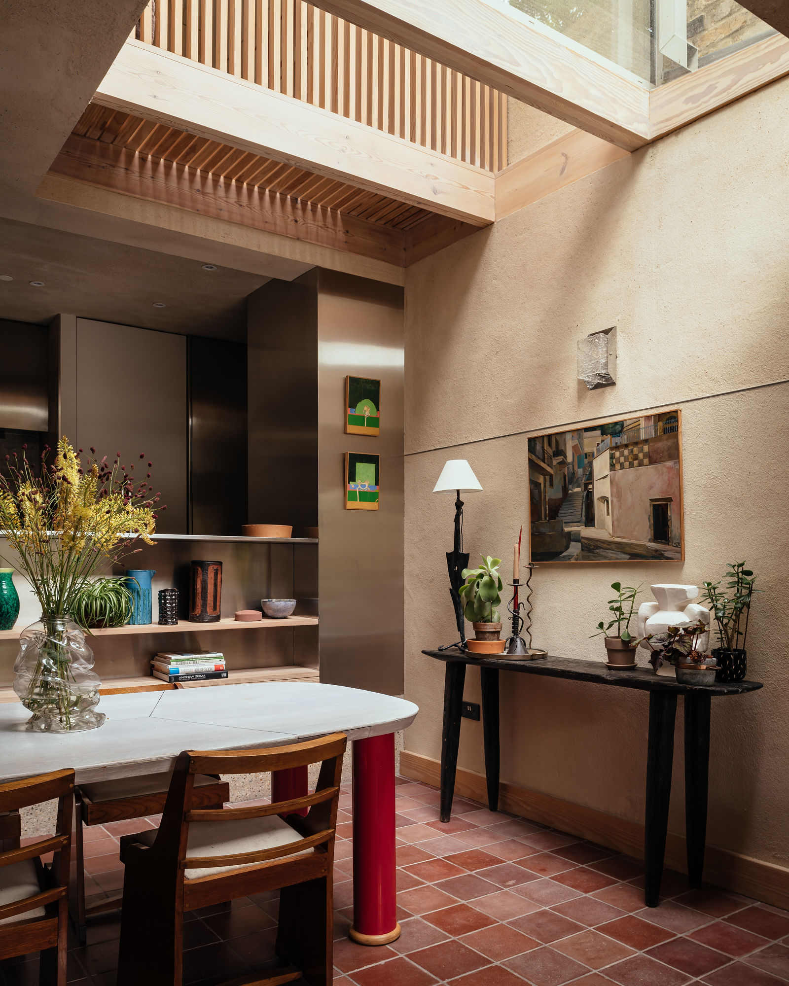 kitchen extension with a red table, a chrome cabinet and a large rooflight overhead