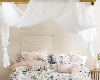 A white bedroom with palm print bedding and canopy