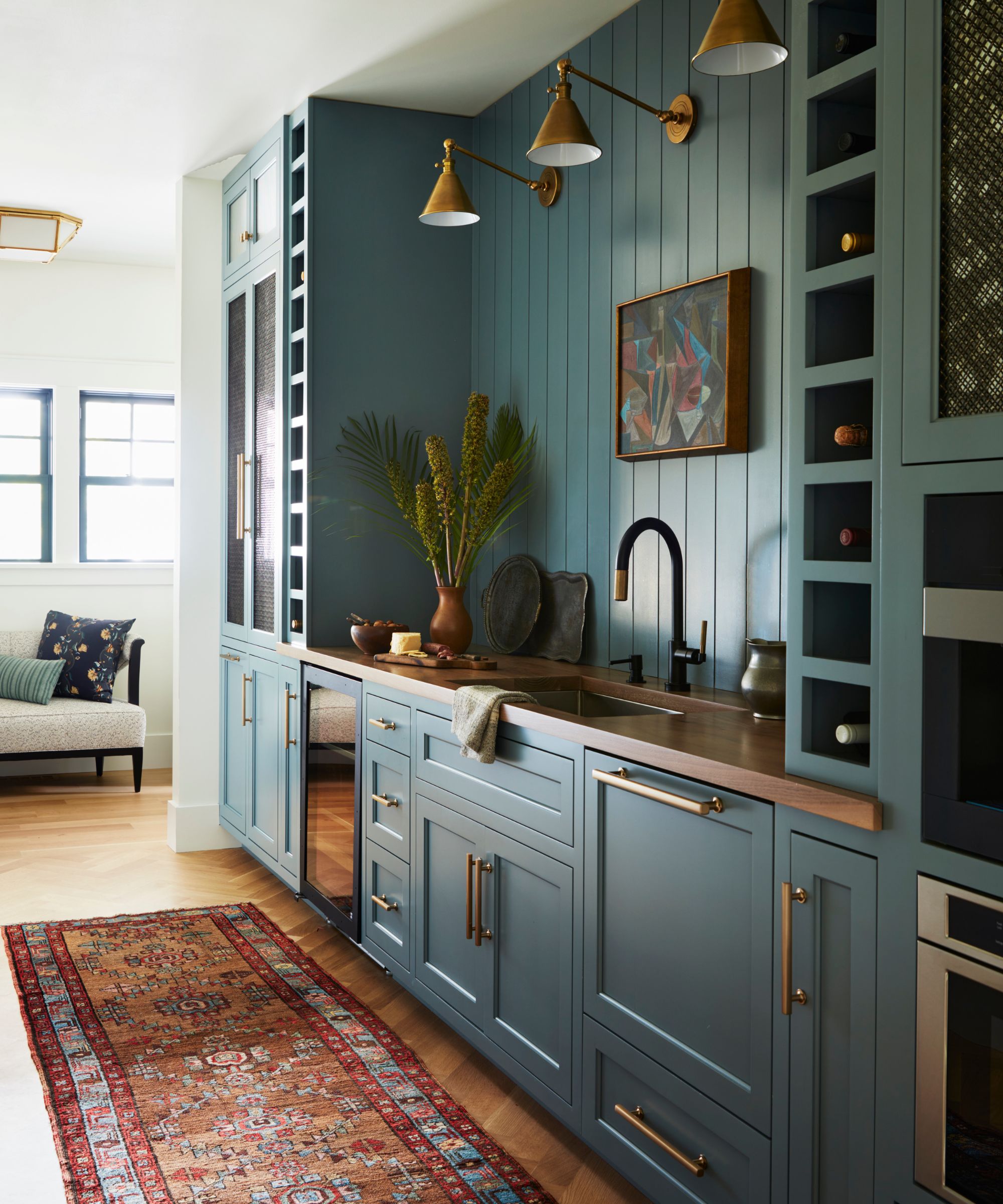 boot room back kitchen entryway bar area painted a soft blue green with a sink, wine racks, mini fridge, and a vintage runner rug