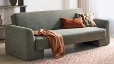 A sofa bed in a living room with a pink and white patterned rug