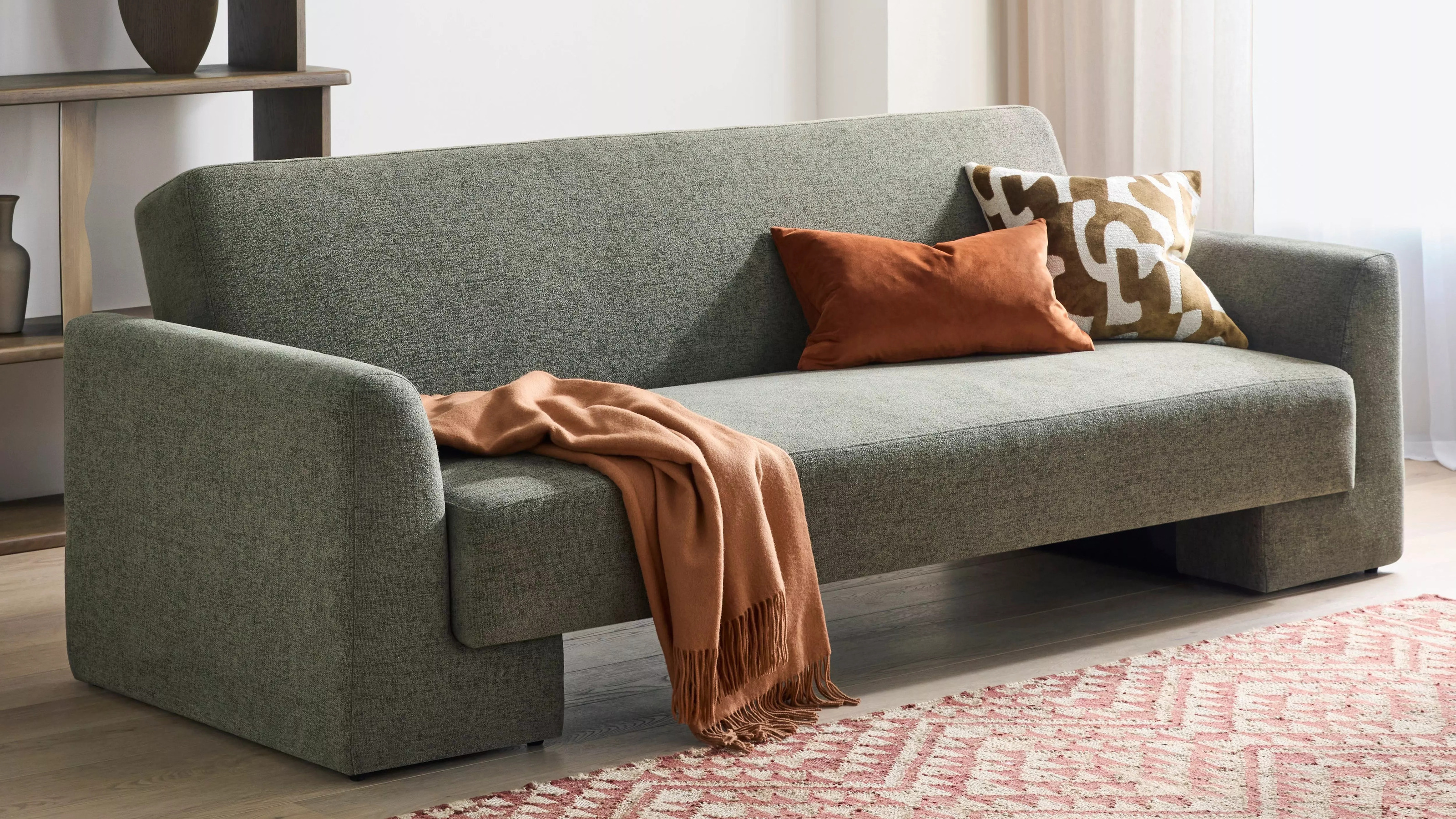 A sofa bed in a living room with a pink and white patterned rug
