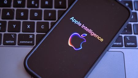 An iPhone with the Apple Intelligence logo on top of a MacBook keyboardm