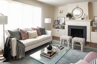 living room with white sofa, throw pillows, blue rug, glass coffee table, and zebra print ottoman