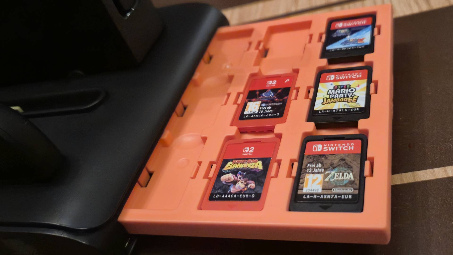 Photo of a red tray pulled out with a plethora of Switch and Switch 2 games sat inside of it.