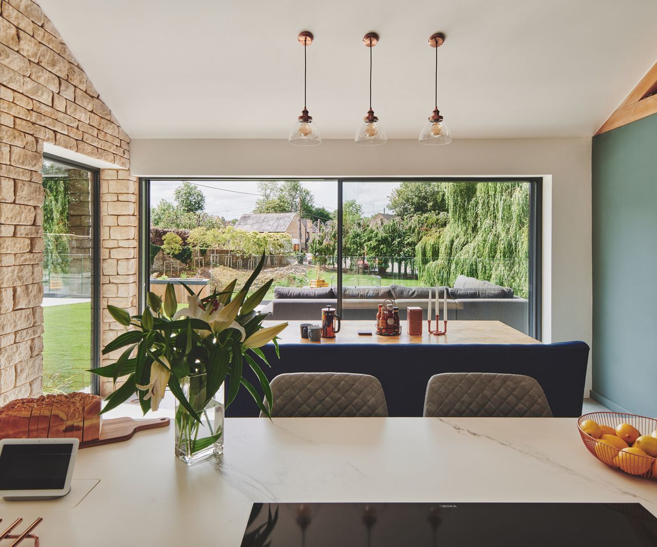 A classic kitchen open plan dining room with a large kitchen island with pendant lighting and light buff floor