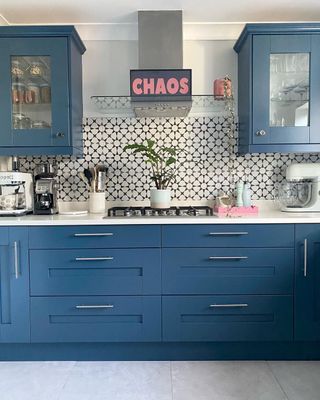 A blue kitchen with an extractor fan with stickers on