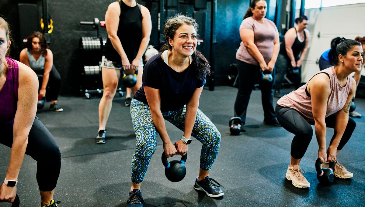 Group of women in gym performing kettlebell deadlift